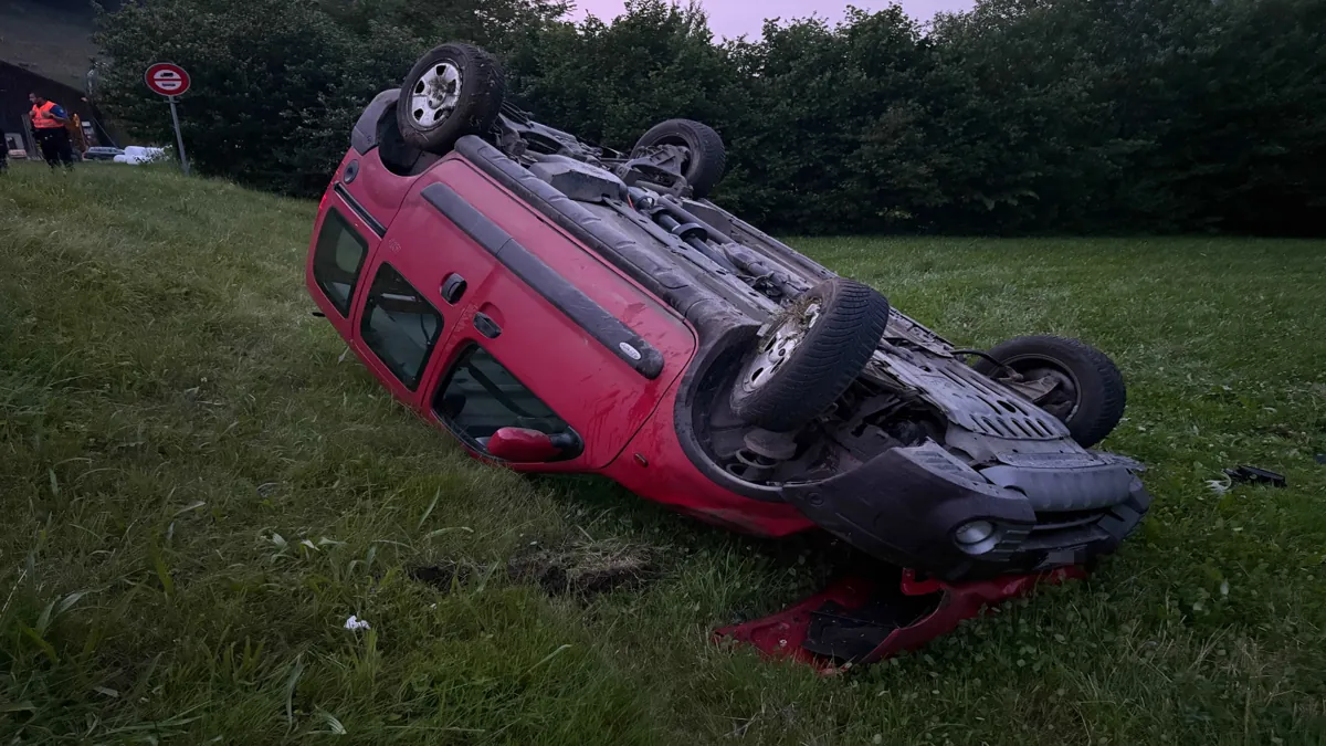 Rotes Auto nach Überschlag stark beschädigt auf dem Dach liegend