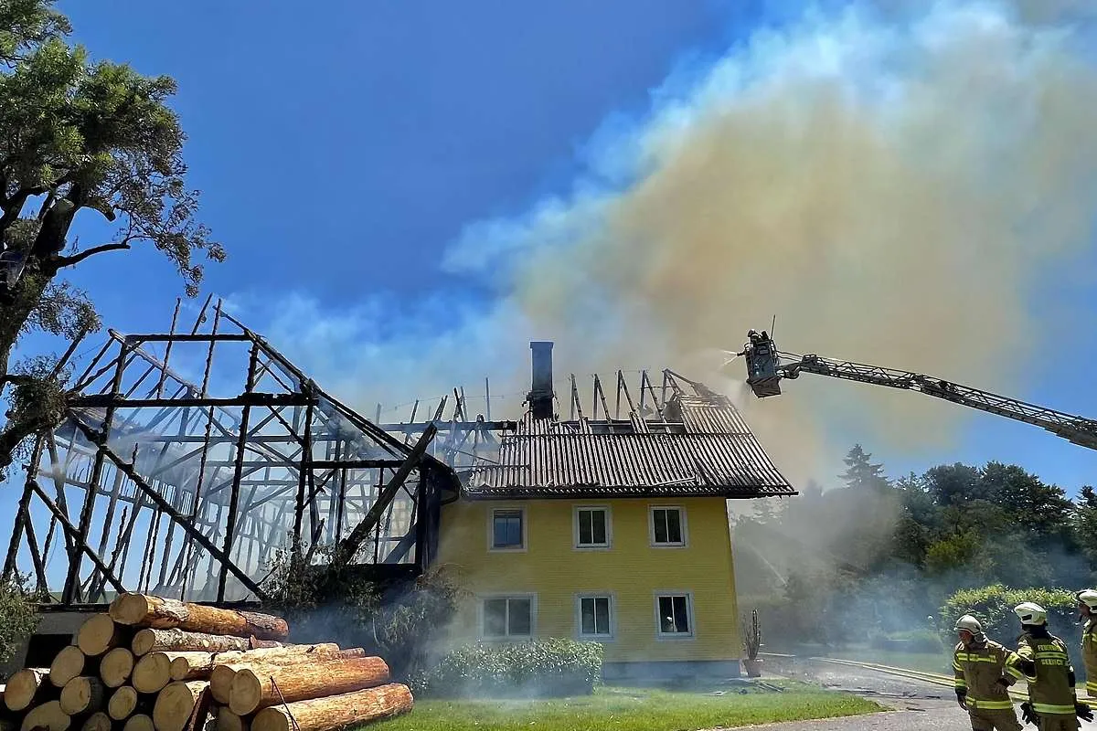 Löscharbeiten mit Drehleiter am Dach eines gelben Wohnhauses in Köstendorf