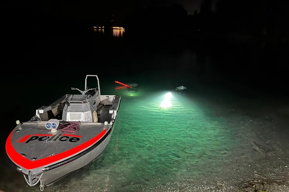Polizeiboot bei nächtlichem Taucheinsatz mit Suchscheinwerfer im See