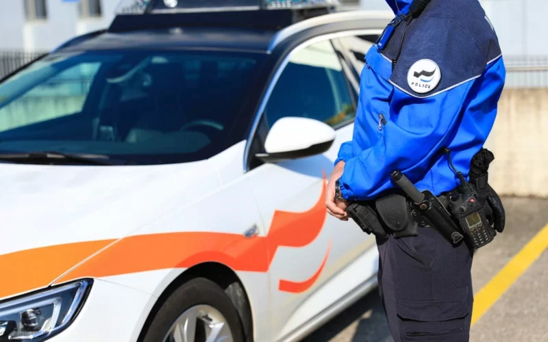Polizist der Freiburger Kantonspolizei vor Einsatzfahrzeug in Uniform