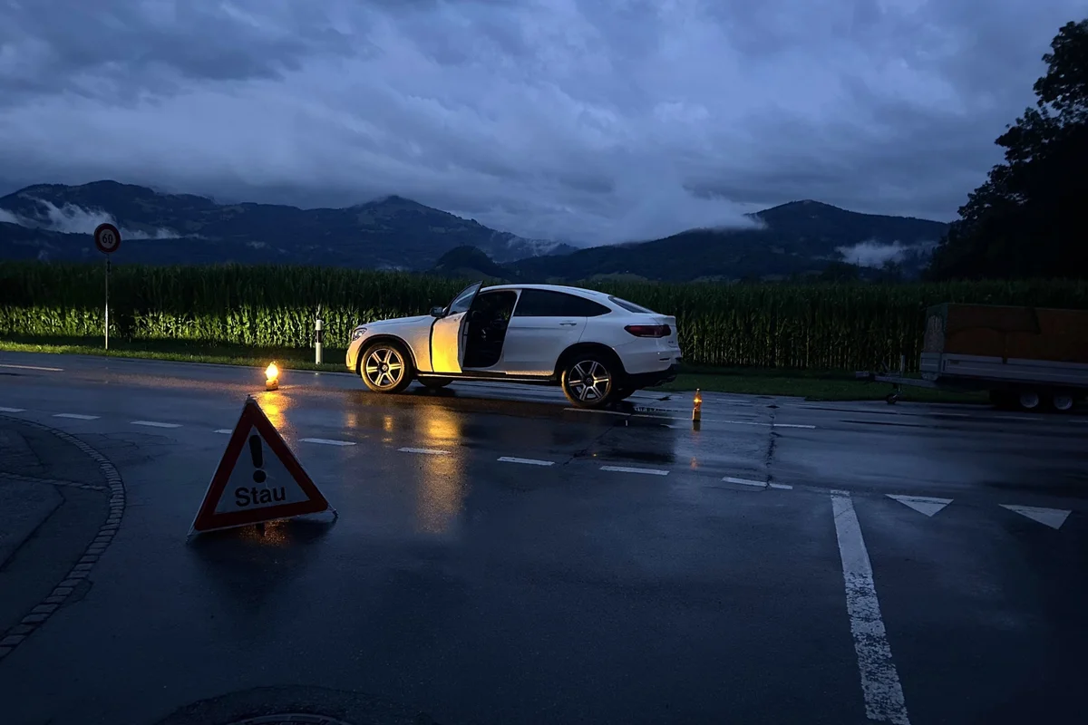 Warnschild „Stau“ bei einem Auto mit Anhänger in der Dämmerung