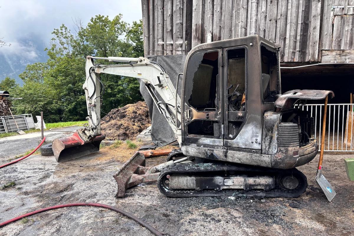 Ausgebrannter Bagger in Mollis nach Brand, direkt neben einer Holzscheune.
