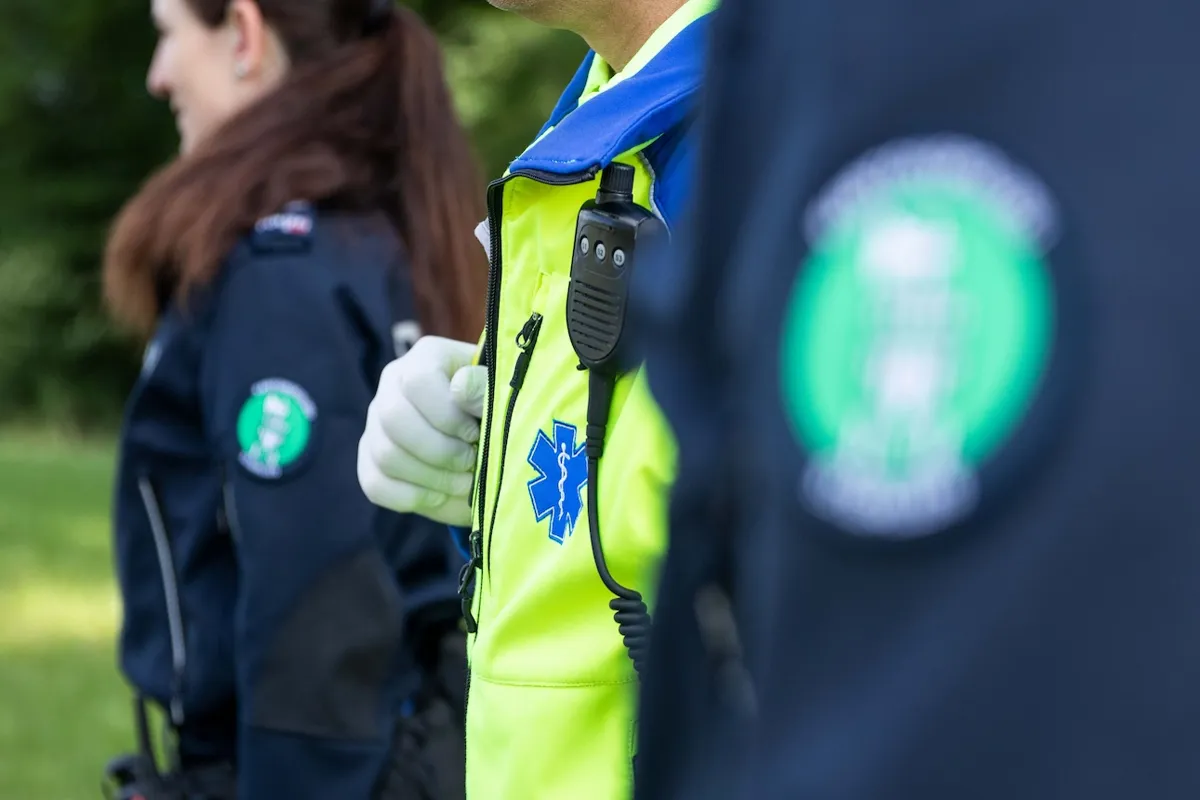 Rettungssanitäter mit Funkgerät und Polizisten im Hintergrund