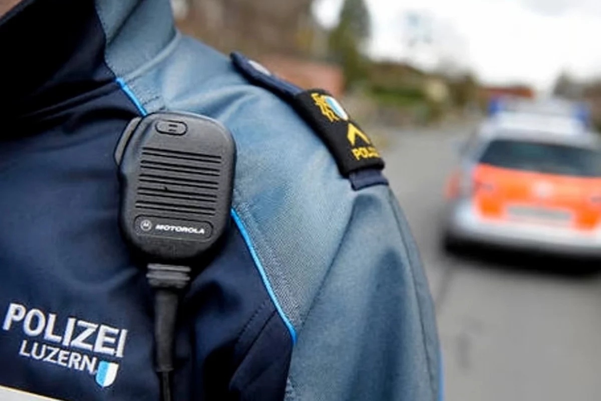 Polizist der Luzerner Polizei mit Funkgerät, im Hintergrund Einsatzfahrzeug