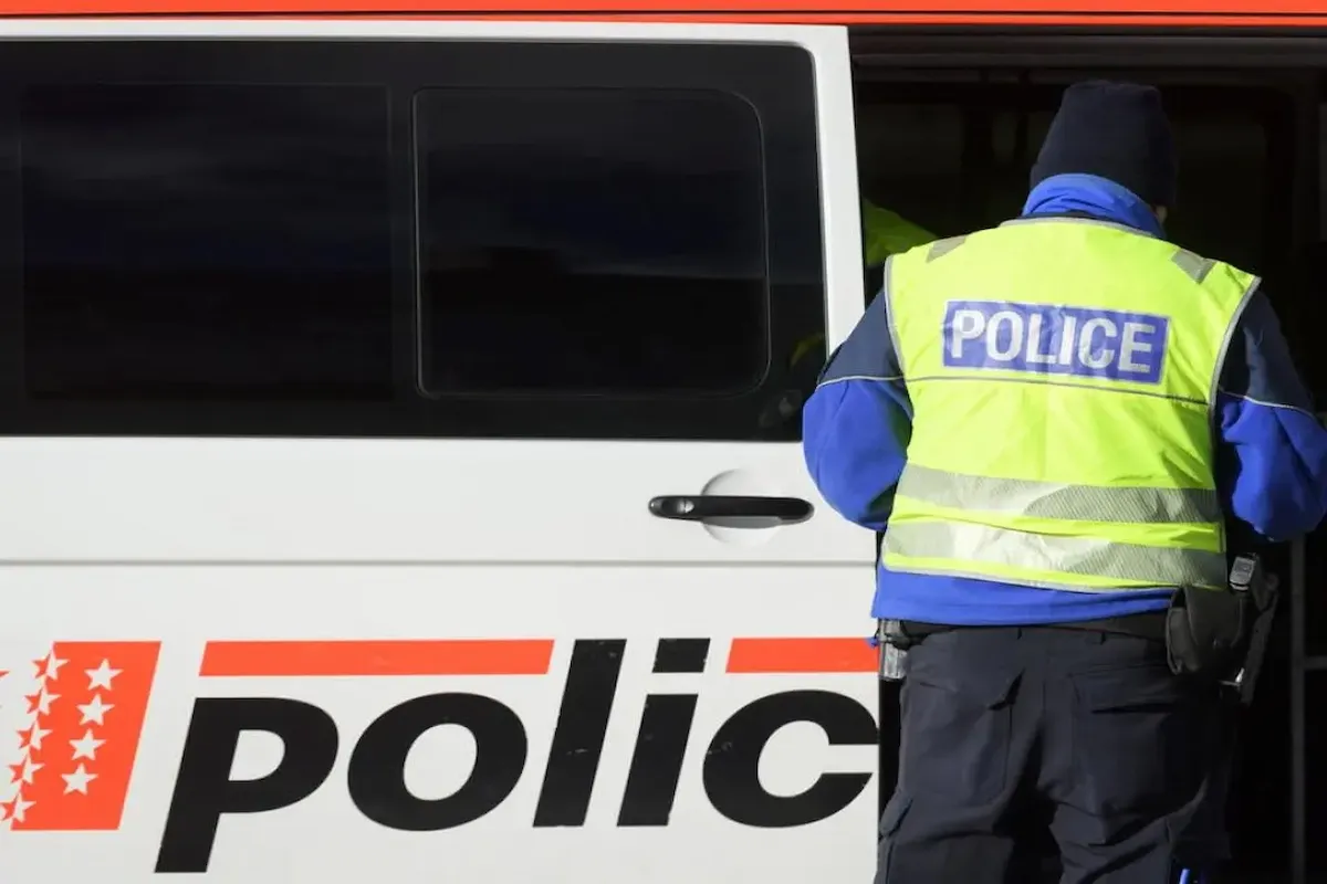 Polizist mit Leuchtweste vor Einsatzfahrzeug der Kantonspolizei Wallis