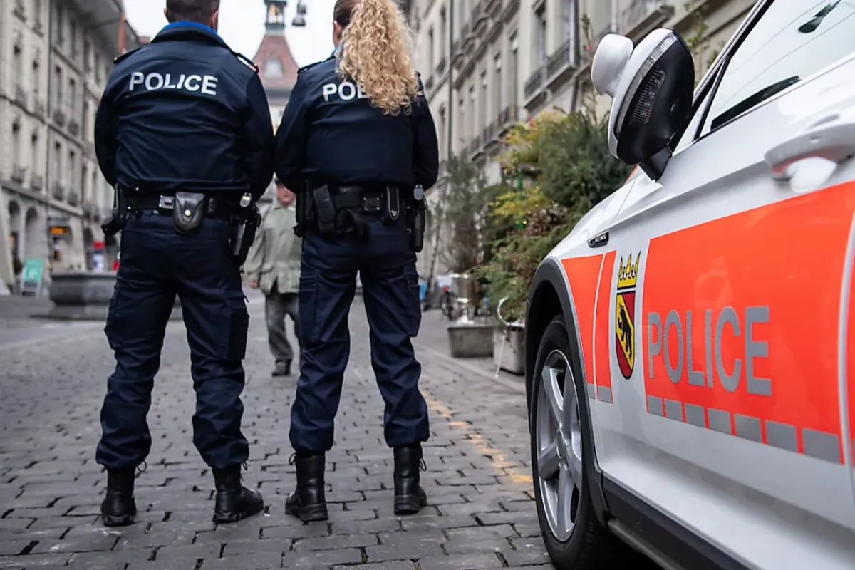 Zwei Polizisten der Kantonspolizei Bern neben einem Einsatzfahrzeug in der Stadt